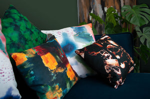 a collection of naruse design cushions displayed on a teal sofa including the summer burst cushion at the front